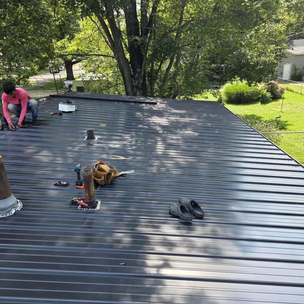 Metal Roof Installation — St. Louis Roof Cost Guide Metal roofing installer fitting standing-seam panels during a residential roof project
